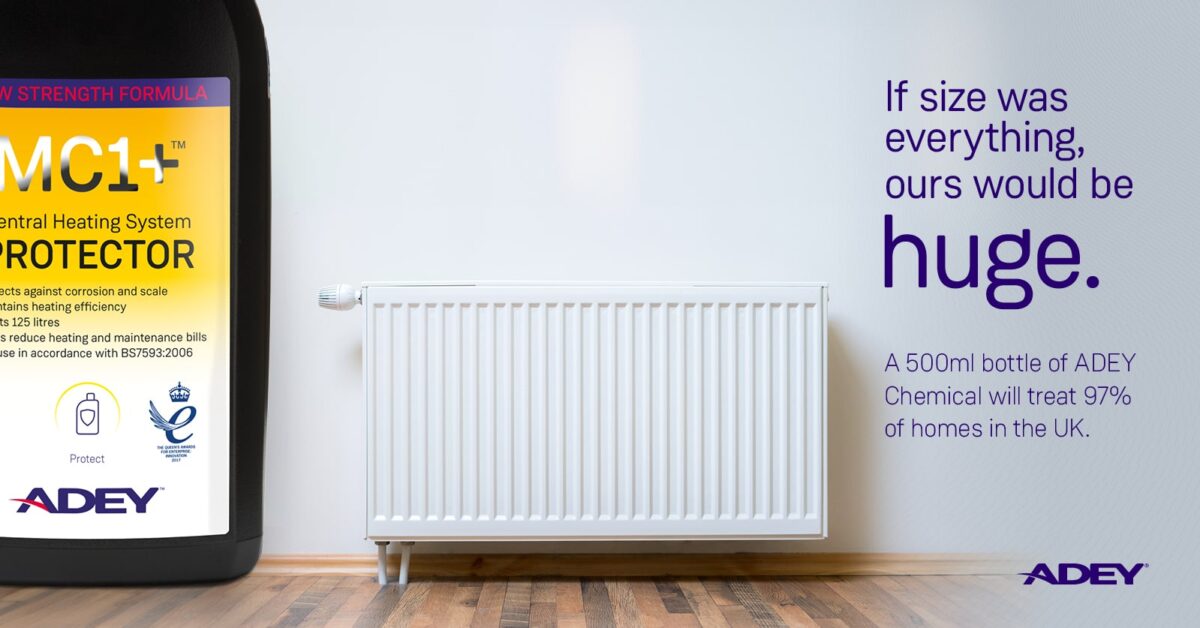 a white radiator in a room, with a large bottle of ADEY chemical